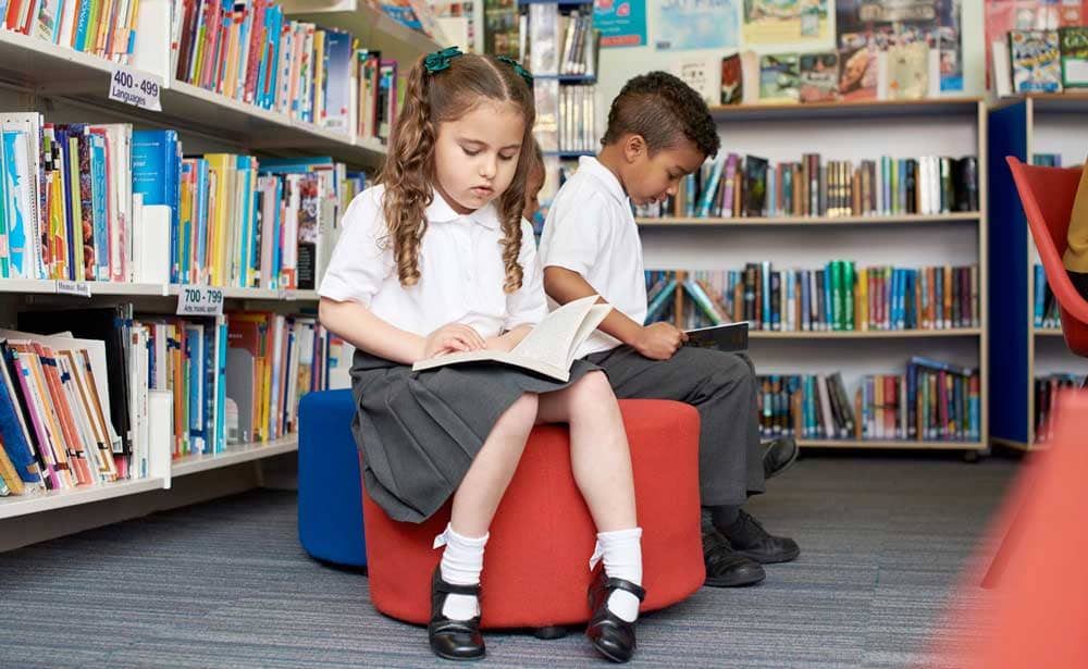 Little boy and girl reading books in library.